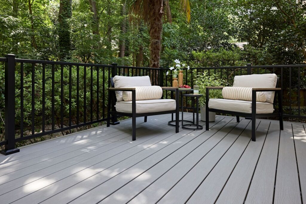 Black Trex Select aluminum railing around a pale gray composite deck surrounded by dense subtropical planting.