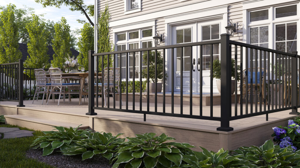Black Trex Select aluminum railing around a low sand-toned composite deck at a white cottage.