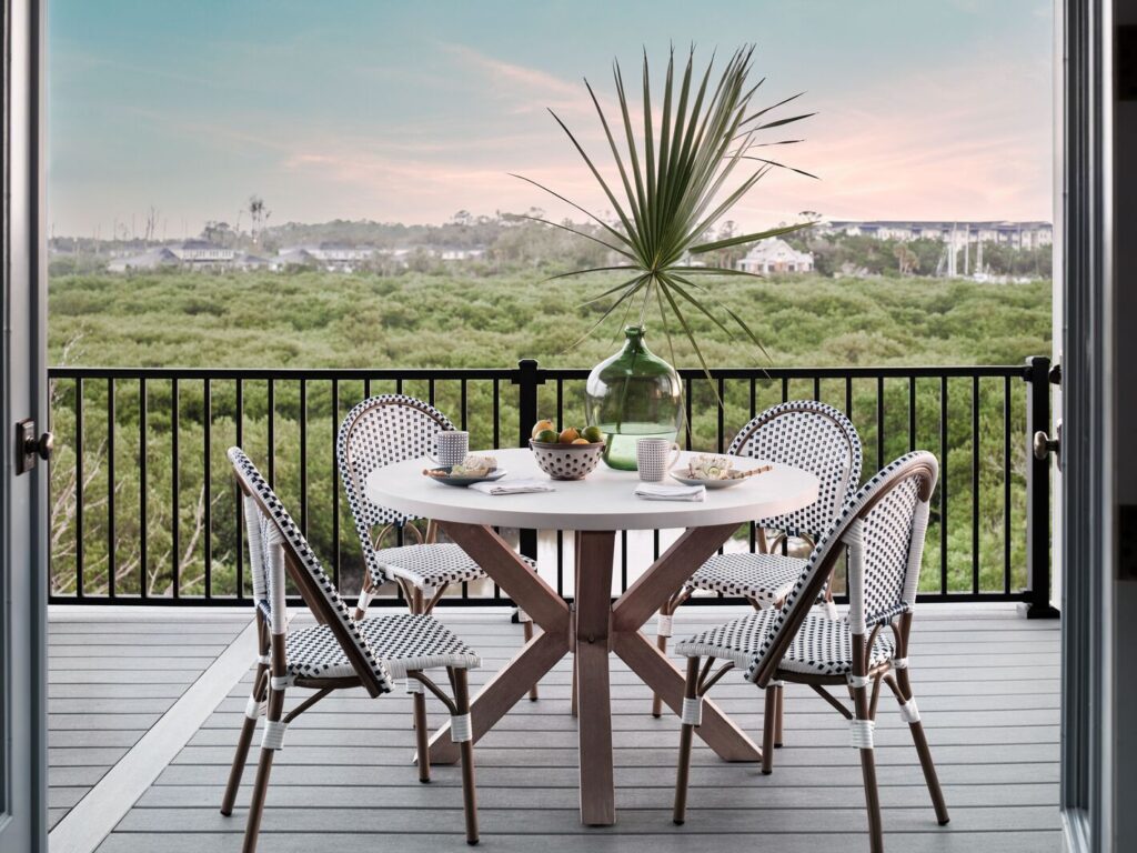 Black Trex Signature aluminum railing on a gray composite balcony with a dining table and a mangrove and marina view.