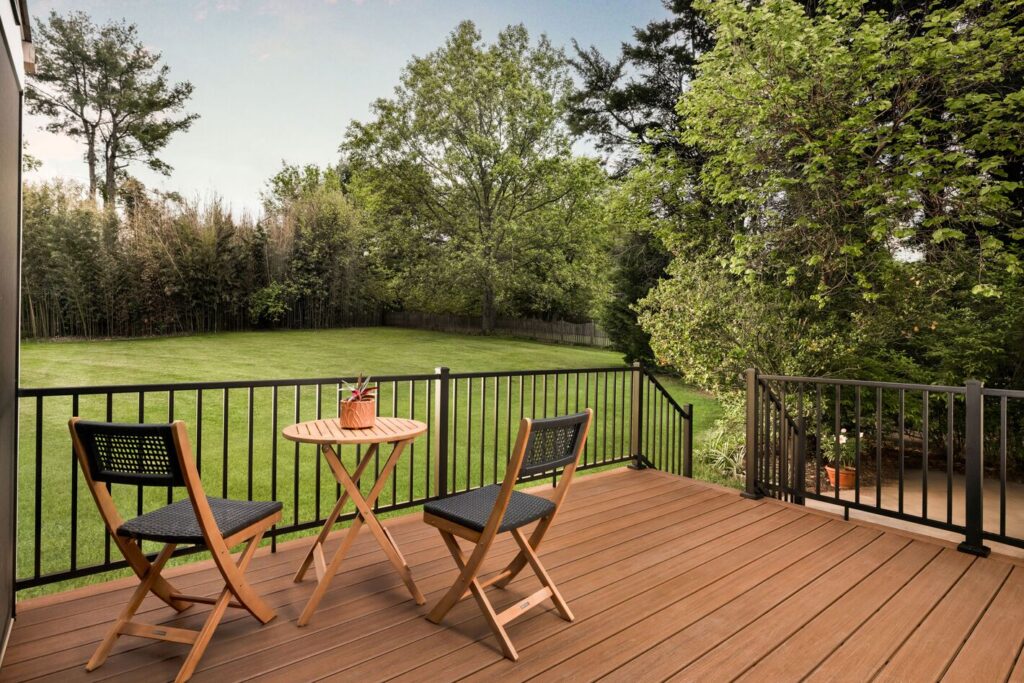 Black Trex Signature aluminum railing with square balusters on a warm brown composite deck overlooking a lawn, metal deck railing ideas for backyards.