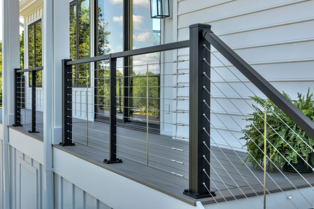 Trex Signature X-Series cable railing on a gray composite porch deck and stair flight against white siding.
