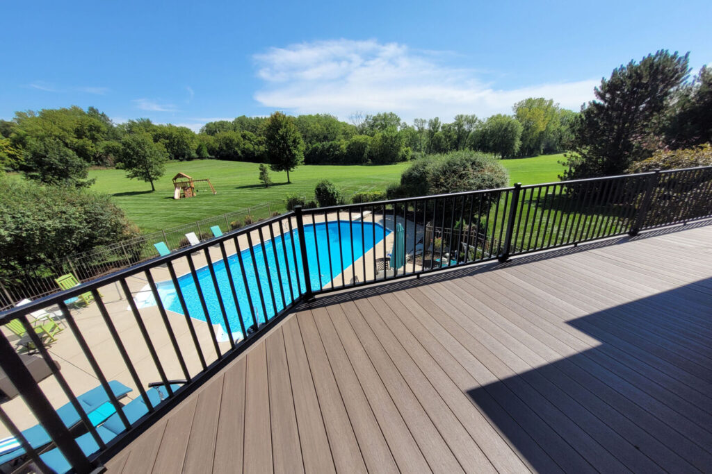 Black Westbury Tuscany aluminum railing along an elevated composite deck overlooking a backyard pool.