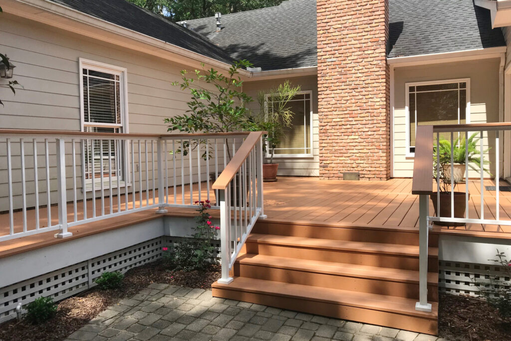 White Westbury Tuscany aluminum railing with a wood-look drink rail cap on a warm composite deck and steps, two-tone metal deck railing ideas.