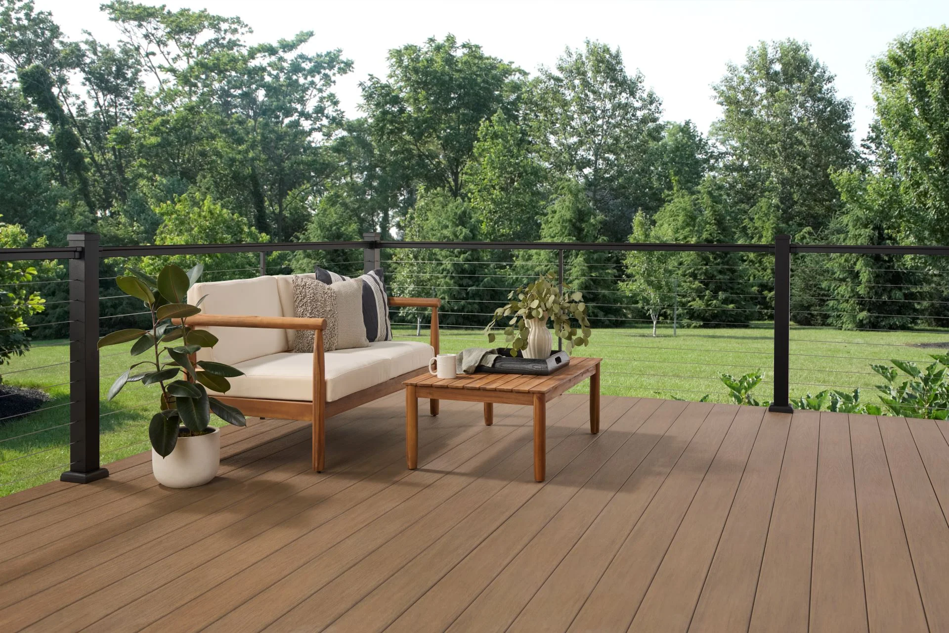 Wolf Serenity PVC decking in a caramel wood tone with black cable railing and teak patio furniture