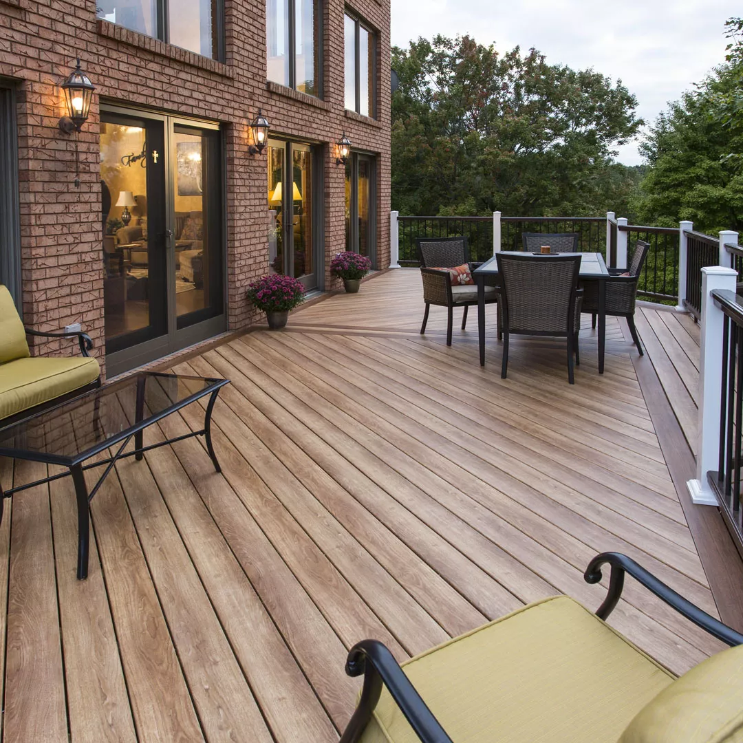 Zuri PVC decking in a warm reddish hardwood tone on a raised deck bordered by potted evergreens and ferns