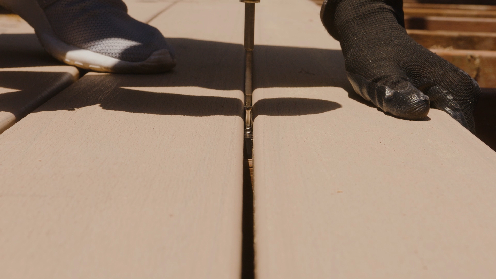 Installer fastening composite deck boards with consistent spacing between each board.