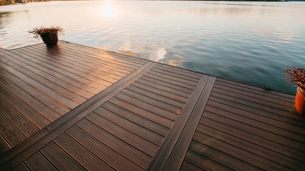 Envision deck ideas featuring Distinction Shaded Auburn decking with framed board sections beside calm waterfront views.