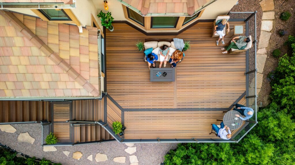 Envision deck ideas featuring Distinction Spiced Teak decking with dark accents, multiple seating zones, stairs, and black railing.
