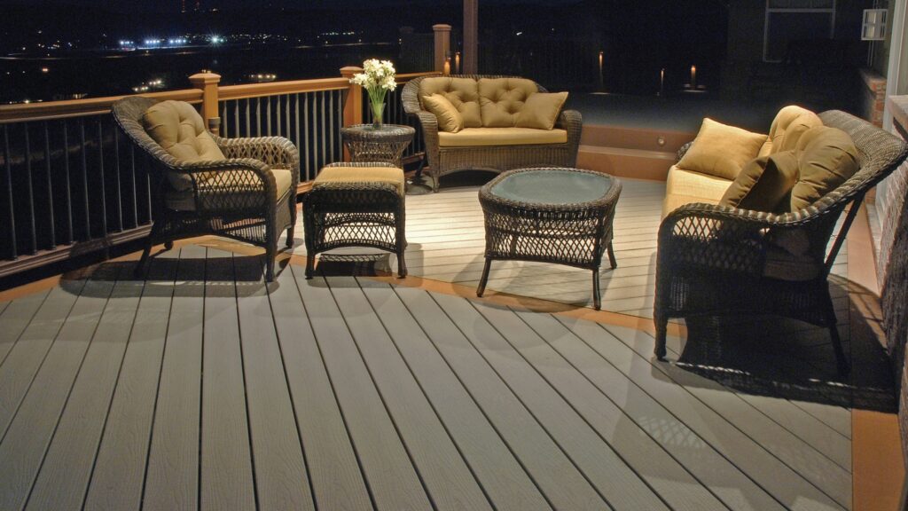 Envision EverGrain Cape Cod Grey deck with warm border boards, wicker seating, two-tone railing, and evening lighting.