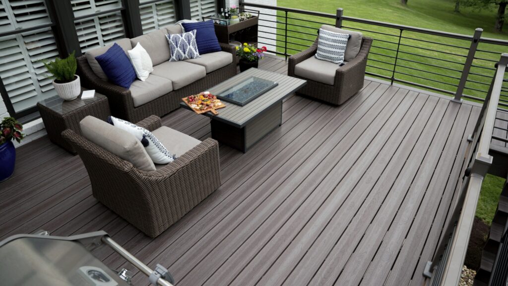 Envision Ridge Premium Gunstock deck with woven lounge furniture, rectangular fire table, and dark horizontal railing.