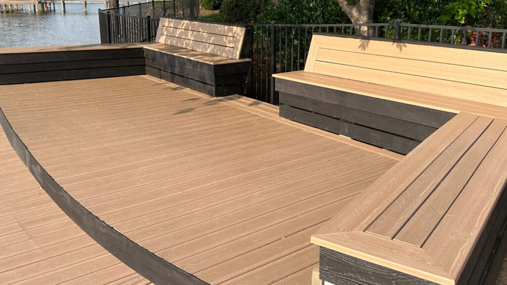 Envision Ridge Premium Sandstone waterfront deck with curved edge, built-in benches, black accents, and open seating space.