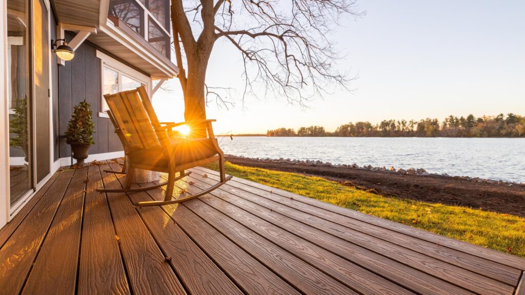 Envision Ridge Premium Vintage Oak lakeside deck with wooden rocking chair, open shoreline, and warm sunset views.