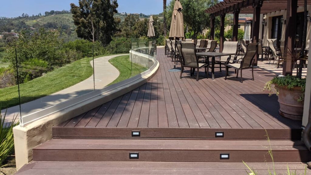 Fiberon Concordia Symmetry Burnt Umber deck with curved glass railing and hillside views.
