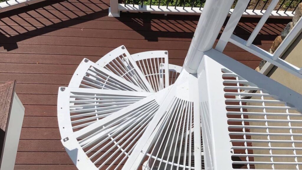 Fiberon Concordia Symmetry Cinnabar decking beneath a white spiral staircase and railing.
