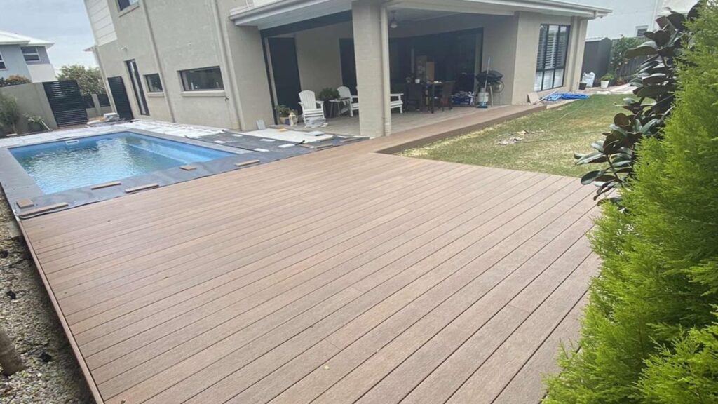 Fiberon Concordia Symmetry Warm Sienna decking surrounding a backyard swimming pool and covered patio.