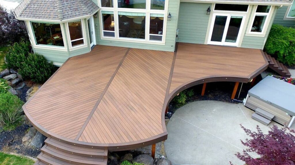 Fiberon Good Life Bungalow curved deck with dark contrasting borders beside a backyard hot tub.