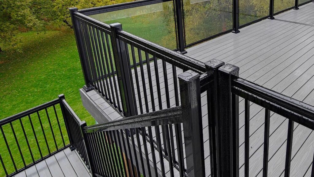 Fiberon deck ideas featuring Good Life Weekender Cottage decking with black railing, glass panels, and stairs.
