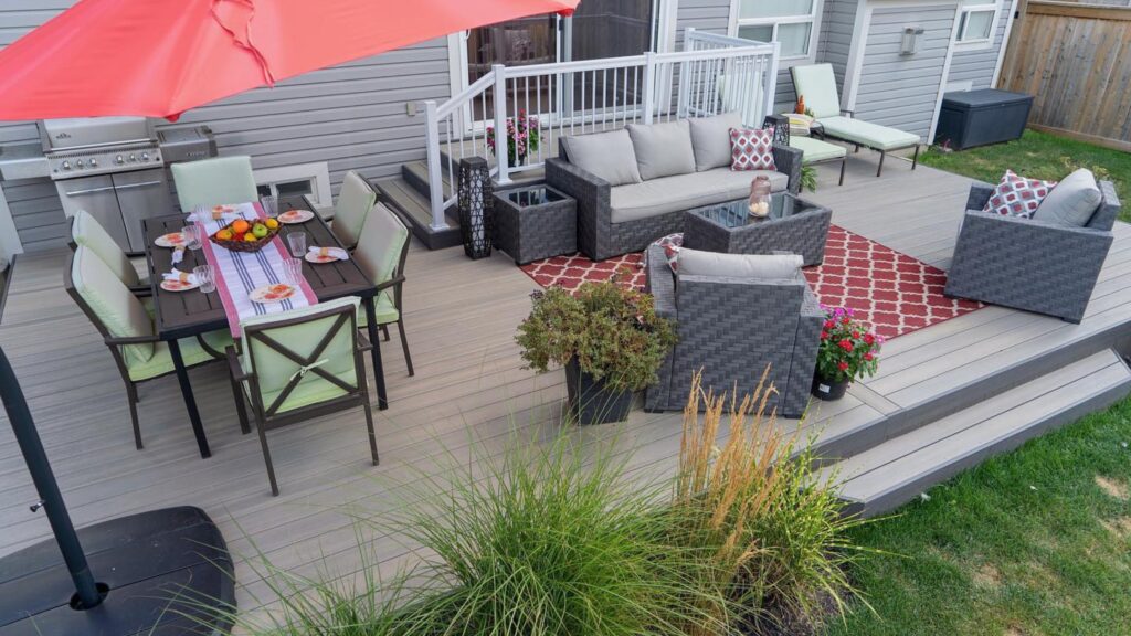 Fiberon Paramount Sandstone PVC deck with outdoor dining, lounge furniture, white railing, grill, and wide steps.