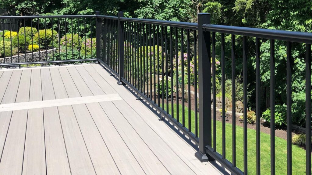 Fiberon Promenade Shaded Cay PVC decking with black railing and a contrasting accent board overlooking a landscaped yard.