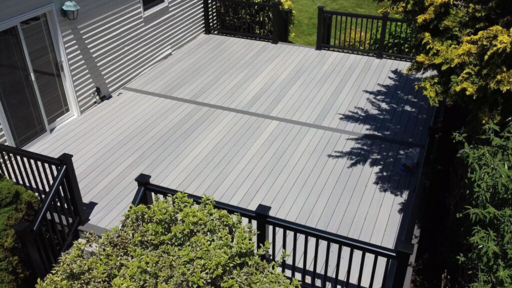 Fiberon Sanctuary Chai and Earl Grey deck with dark divider board and black railing in a landscaped backyard.