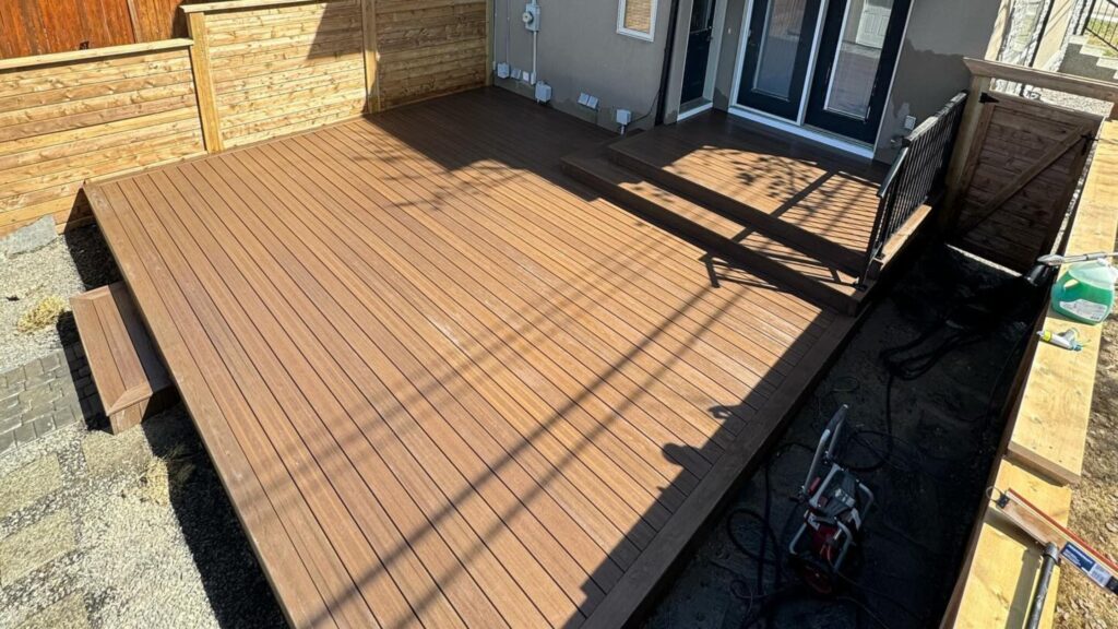 Fiberon Sanctuary Espresso brown deck with dark perimeter border, shallow steps, and black railing near the house.