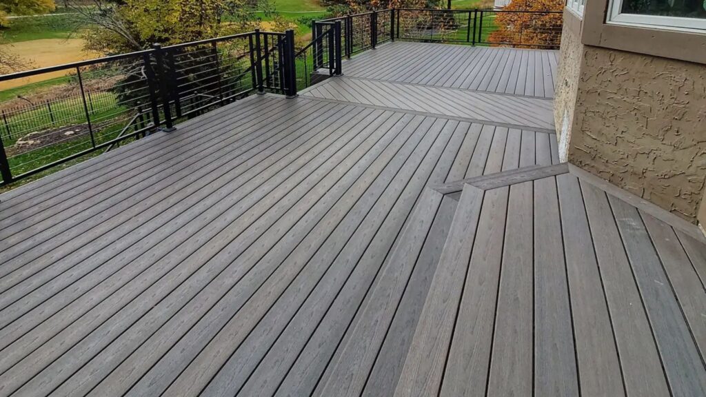 Fiberon Sanctuary Latte deck with black horizontal cable railing and changing board directions overlooking a landscaped yard.