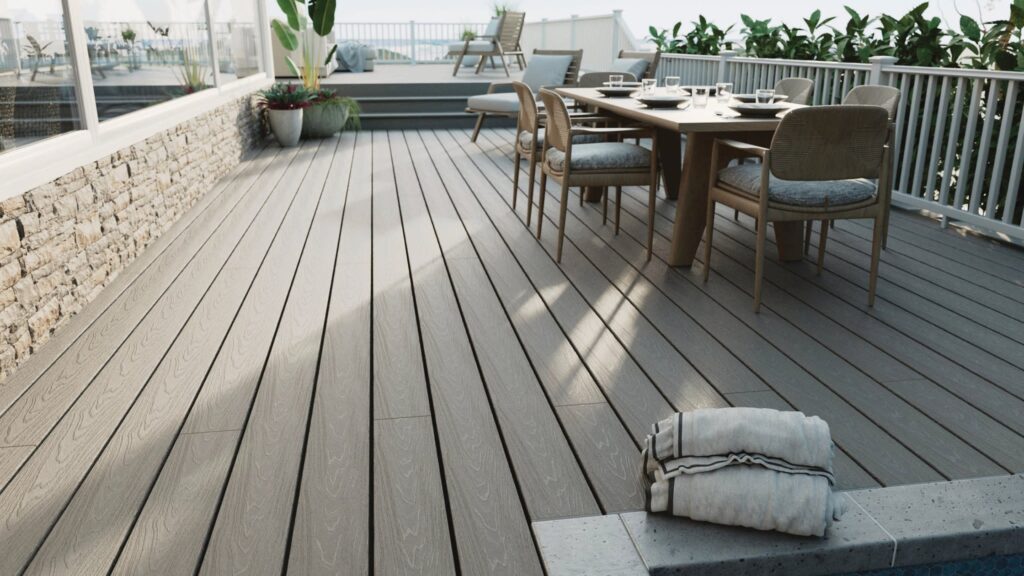 Fiberon Veranda Stone Gray poolside deck with outdoor dining furniture, white railing, and raised lounge area.