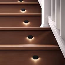 Trex oval riser lights illuminating brown deck stairs at night.