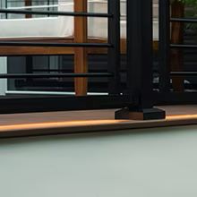 Trex under-rail light creating a warm glow beneath black deck railing.